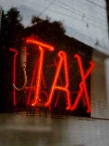 red neon sign that says "tax"